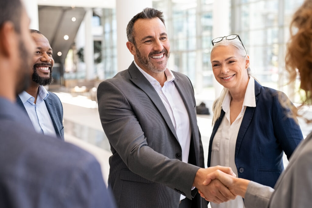 man shaking a woman's hand. People around them smiling
